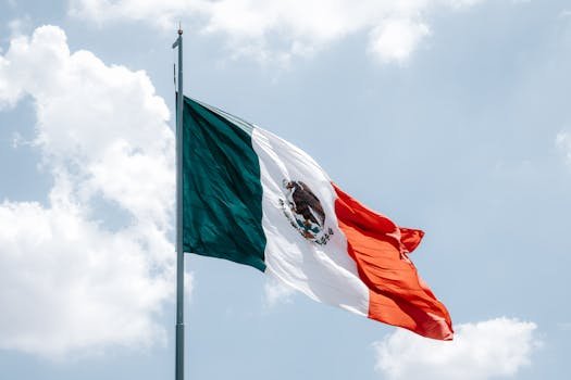team-2 Vibrant Mexican flag waving against a bright blue sky in Mexico City.